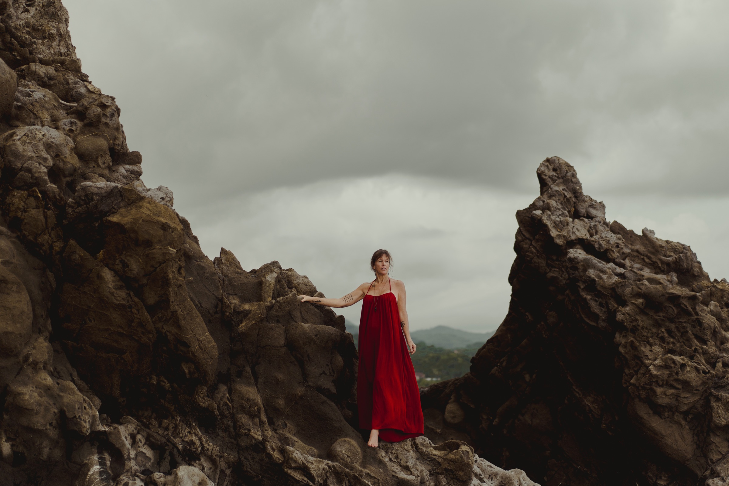 Kerry in a red dress on the rocks by the sea