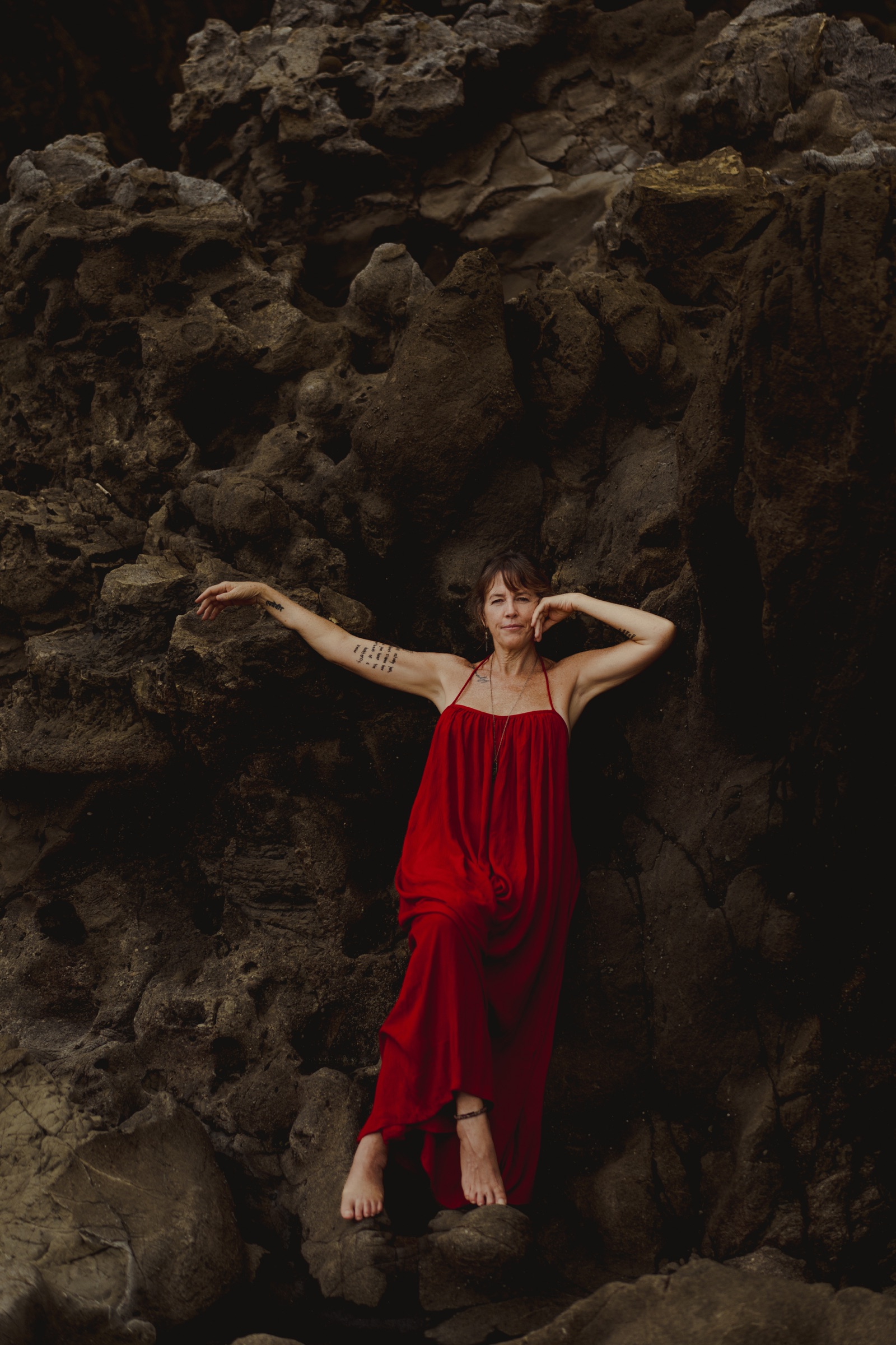Kerry in a red dress leaning against the rocks
